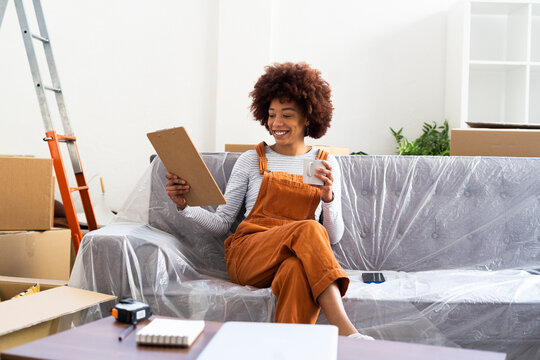 Smiling woman holding checklist on clipboard in new home
