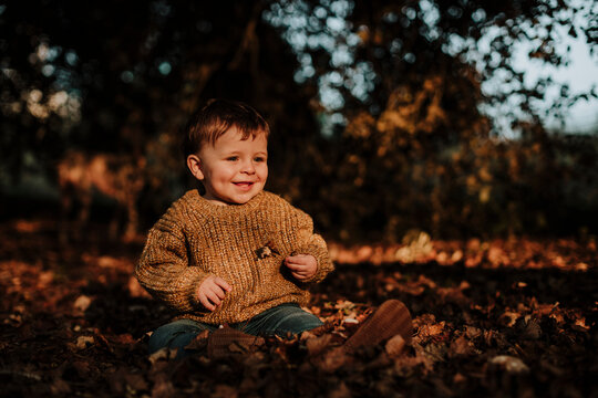 family with a baby exploring the autumn in the forest and having fun with the leaves in Rub√≠ Barcelona Spain