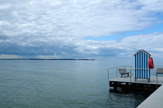 Germany, Schleswig Holstein, Stein, Jetty with blue and white beach cabin on Baltic Sea under cloudy sky