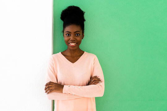 Smiling woman standing with arms crossed against multi colored wall