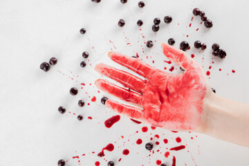 Blackcurrant confiture on white background and red syrup on the hand of a man