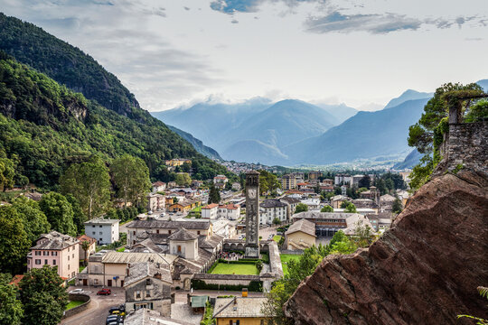 Parrocchia Di San Lorenzo in town by mountain against sky seen from Parco Archeologico Botanico del Paradiso, Valchiavenna, Chiavenna, Province of Sondrio, Lombardy, Italy