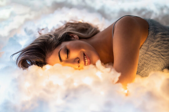 Smiling young woman sleeping on illuminated cottons