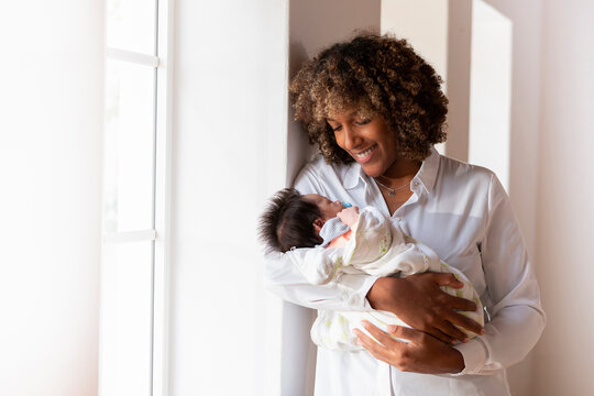 Happy mother smiling while looking at baby standing at home