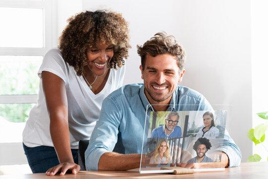 Couple talking with friends on video conference over transparent screen at home