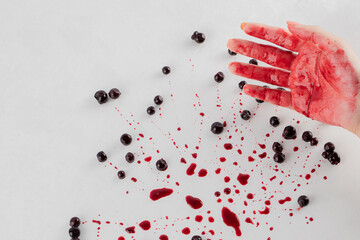 Blackcurrant confiture on white background and red syrup on the hand of a man