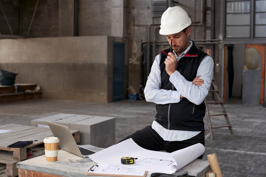 Male architect thinking while analyzing blueprint on table in building
