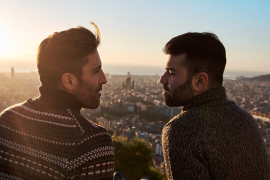 Romantic gay couple looking at each other with cityscape in background, Bunkers del Carmel, Barcelona, Spain