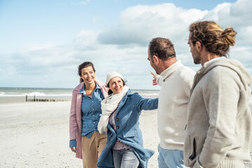 Group of adult friends greeting on coastal beach