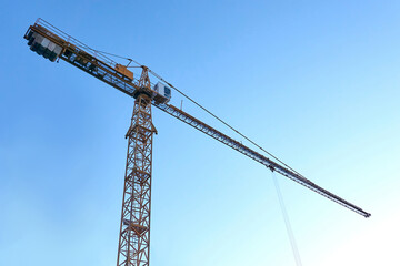 Tall construction crane against the blue sky. Tower crane.