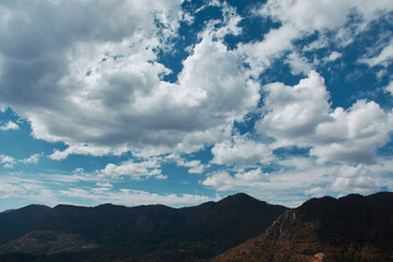 Fototapeta na wymiar cielo azul con nubes con fondo de montañas 