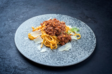 Modern style traditionelle italienisches Ragu alla Bolognese Sauce mit Linguine Pasta Nudeln und Parmesan Käse serviert als close-up auf einem Keramik Design Teller mit Textfreiraum