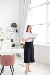 a young female coach works in a home office in a light interior conducts a presentation with laptop, the concept of remote work