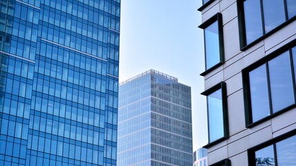 Fototapeta premium Bottom view of modern skyscrapers in business district against blue sky. Looking up at business buildings in downtown.