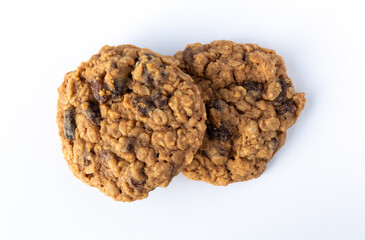 Top view of two homemade oatmeal raisin cookies on a white plate illuminated with natural light.