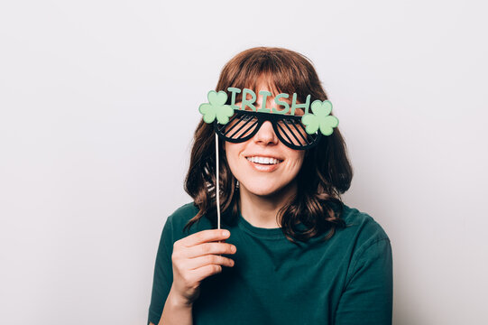Young woman is preparing for the St Patricks Day party with photo booth props, Ireland traditional holiday, 17 March
