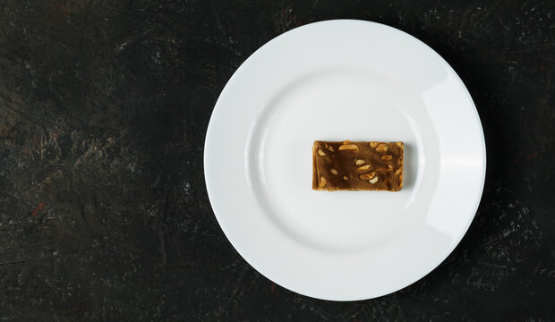 White plate with a piece of sweetness on a dark background
