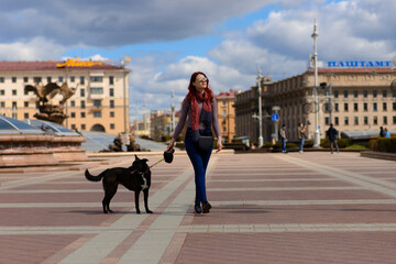 Naklejka premium Beautiful happy young woman with cute black dog have fun on street.