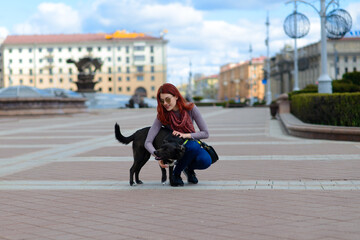 Beautiful happy young woman with cute black dog have fun on street.