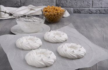 Vegan meringues with whipped aquafaba - chickpea water on baking paper. Bowl with chickpea, whisks nearby. Copy space