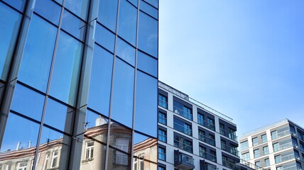 Facade texture of a glass mirrored office building. A beautiful background of an glass office building, reflecting clouds in the windows.