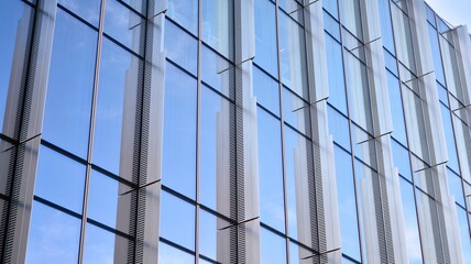 Obraz premium Facade texture of a glass mirrored office building. A beautiful background of an glass office building, reflecting clouds in the windows.