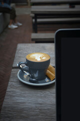 Coffee cup with brown sugar and laptop on a wooden outdoor table