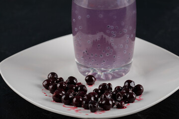Blackcurrant confiture in a white saucer with a glass of juice around