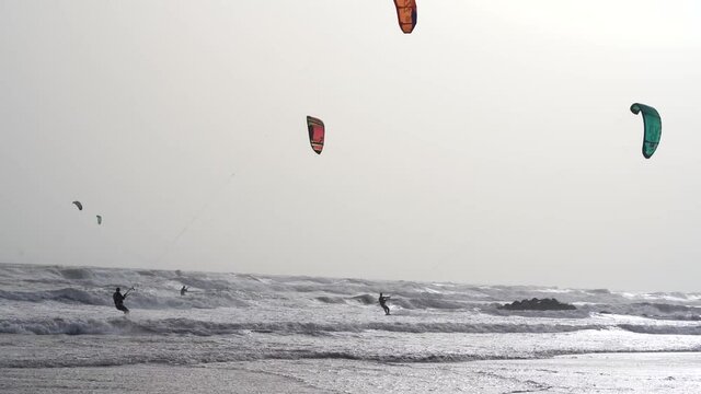 trois kitesurfs aux ralentis qui alignent leurs voiles au milieu des vagues 
