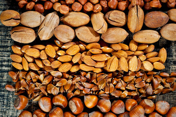Many kinds of nuts close up. Heap of nuts on a black wooden board. Nuts are stacked on the table.