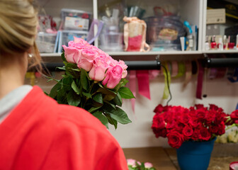Girl holding bunch of pink roses, red roses in the blue tank on the background