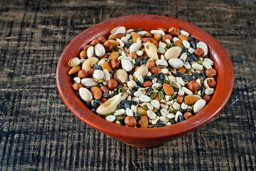 Many types of nuts close up. Texture of different nuts on a wooden board. Clay bowl on a brown table.