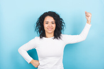 Young brunette woman showing off her arm strength. Women's rights