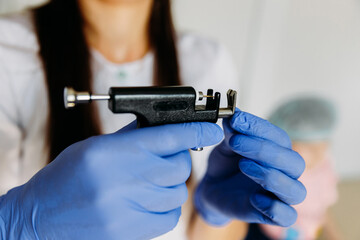 Female cosmetologist holding ear piercing gun.