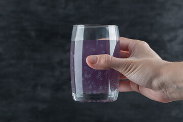 A person holding a glass of purple juice