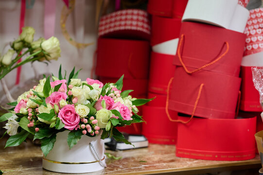 Flower box with pink and white roses on the table, red heart-shape boxes on the table