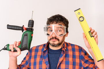 Do-it-yourself man holding a drill and level looking confused