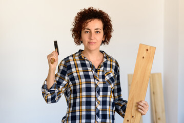 Woman holds a wood and hammer for DIY