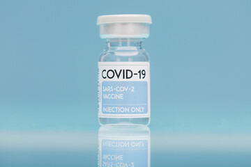 Glass vial with vaccine from COVID 19 placed on table on blue background
