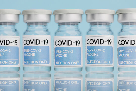 Glass vials with vaccine from COVID 19 placed on table in row on blue background
