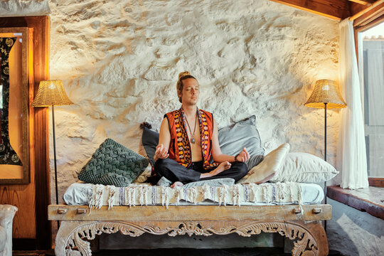 Blond man practicing meditation with closed eyes at home