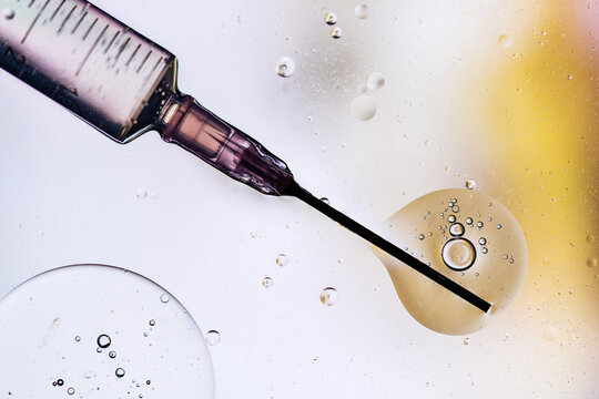 Closeup of needle of syringe filled with vaccine from virus injected in cell on blurred background