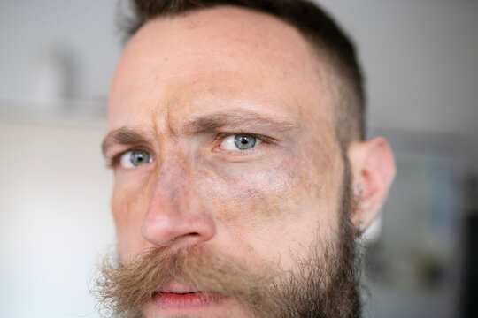 Hipster man with beard looking at camera and with face with movie makeup