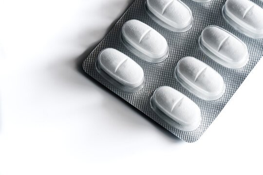 Closeup top view of full frame background of various white pills in plastic blister arranged