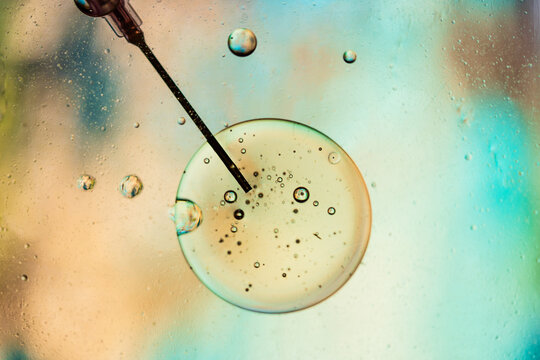 Closeup of needle of syringe filled with vaccine from virus injected in cell on blurred background