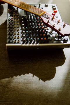 From above mixing console and crop guitar on table on sunlight