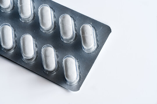 Closeup top view of full frame background of various white pills in plastic blister
