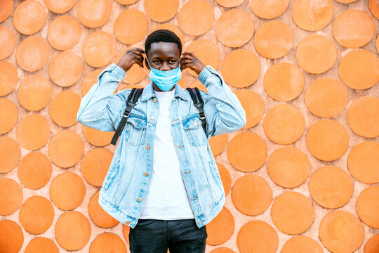 Unrecognizable young contemplative black male in denim jacket and respiratory mask looking away during coronavirus pandemic