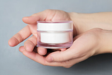 Female hands holding a jar of moisturizer. Beauty treatment, skin care, body care concept. Anti aging cream mockup.
