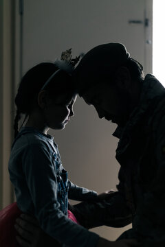Side view silhouette of upset girl touching dad with forehead while seeing off dad to war